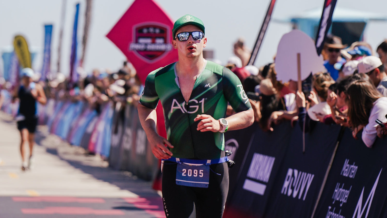 Athlete running in a triathlon with spectators and event banners in the background