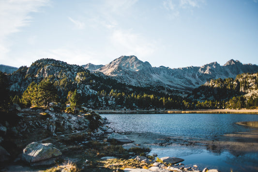 Lake in Andorra surrounded by trees and snowy mountains
