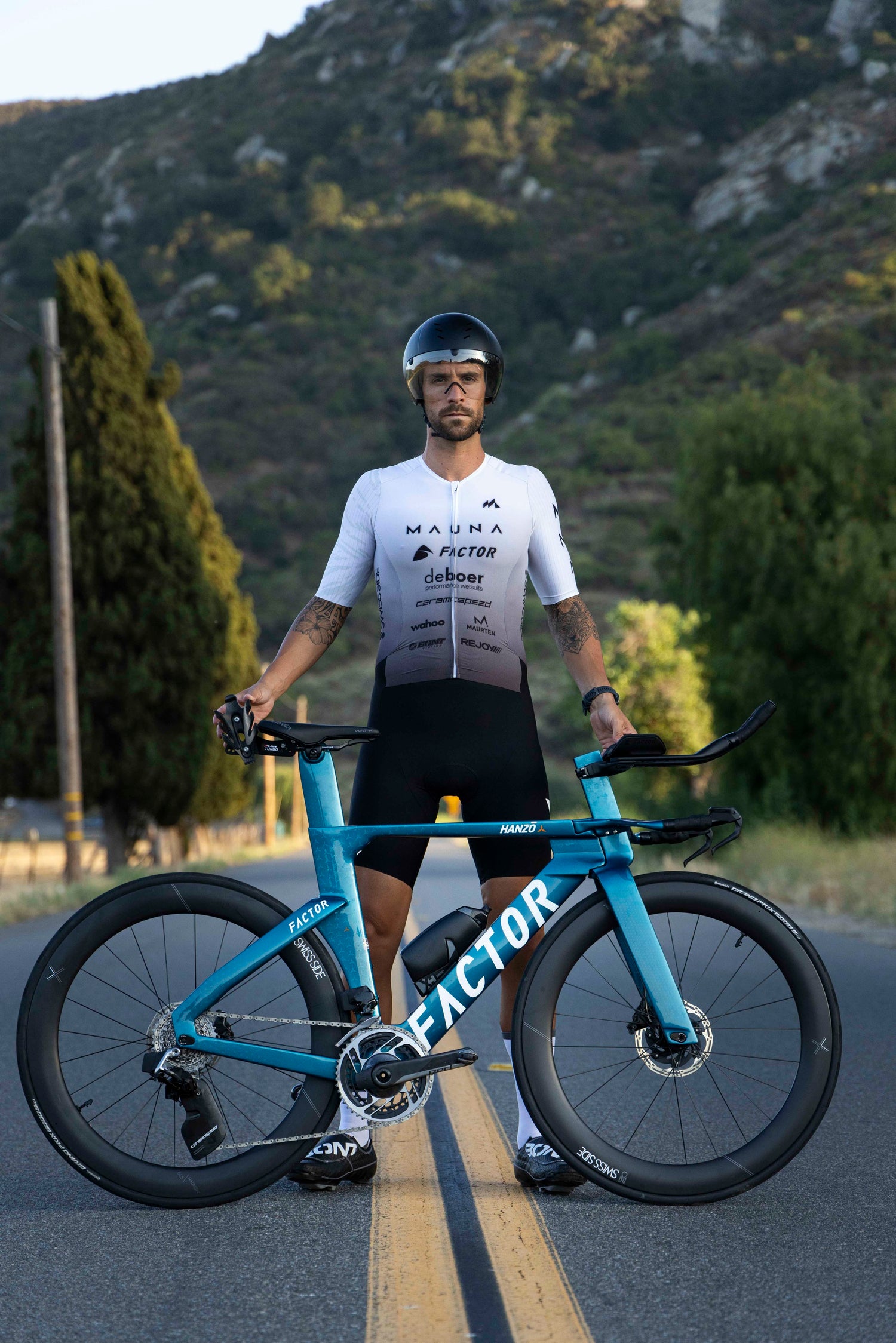 Man standing next to bicycle wearing Mauna's custom triathlon apparel